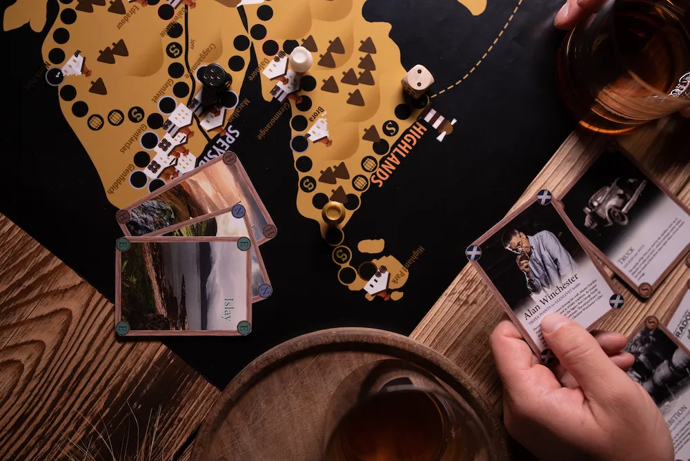 The Whisky Game in action โ board with map of Scotland, character cards, and whisky glass